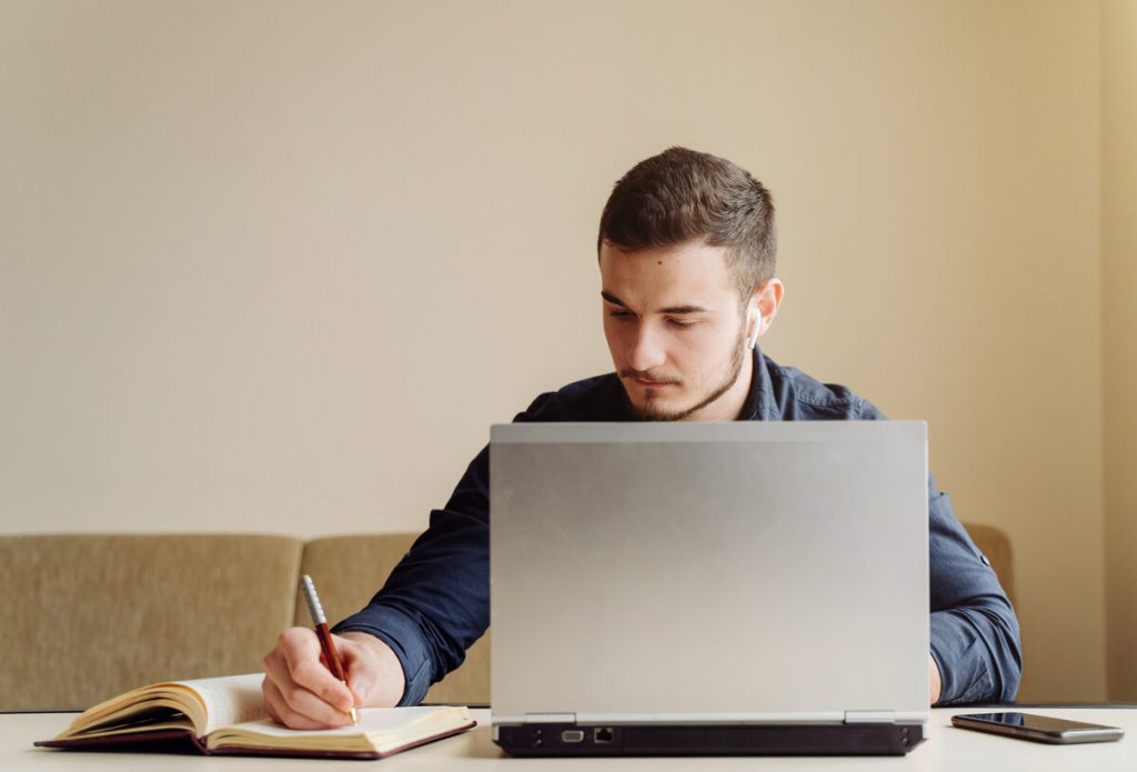 rapaz sentado em frente ao computador a estudar graças ao crédito estudante