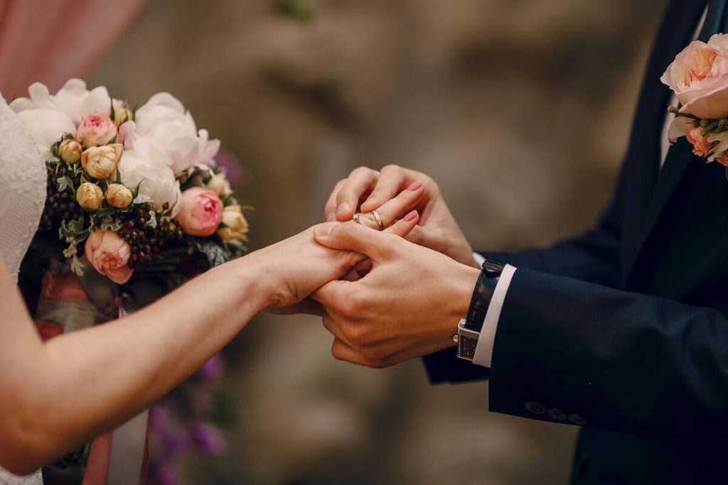 casal a trocar alianças em cerimónia paga com crédito para casamento